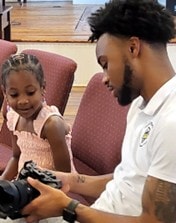 Young man showing a student the complexities of a digital camera — high technology program at UniFIED Efforts